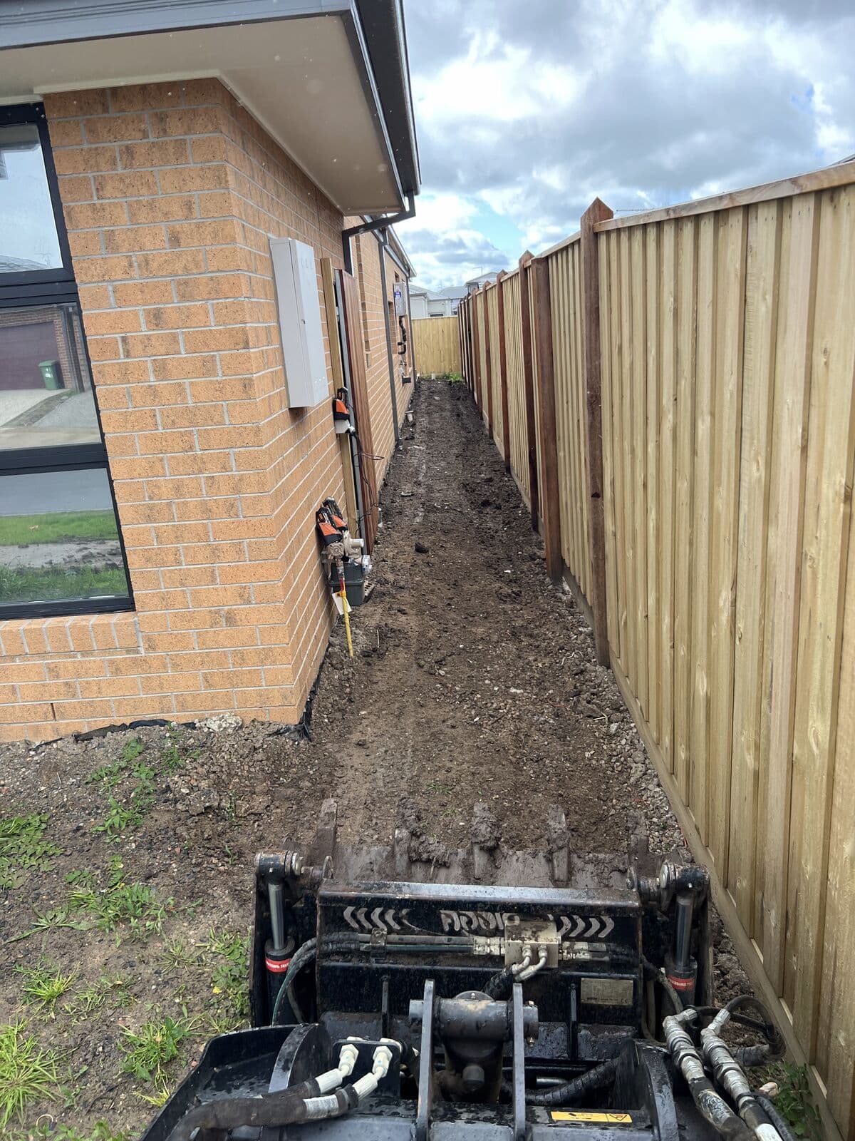 Excavation along a narrow, fenced side-yard access path