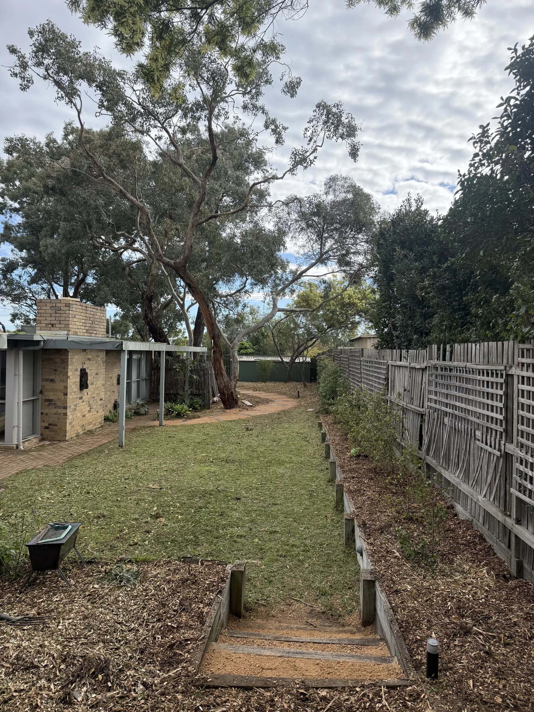Backyard after a clean-up, with mown lawn, fresh mulch and a cleared gravel path