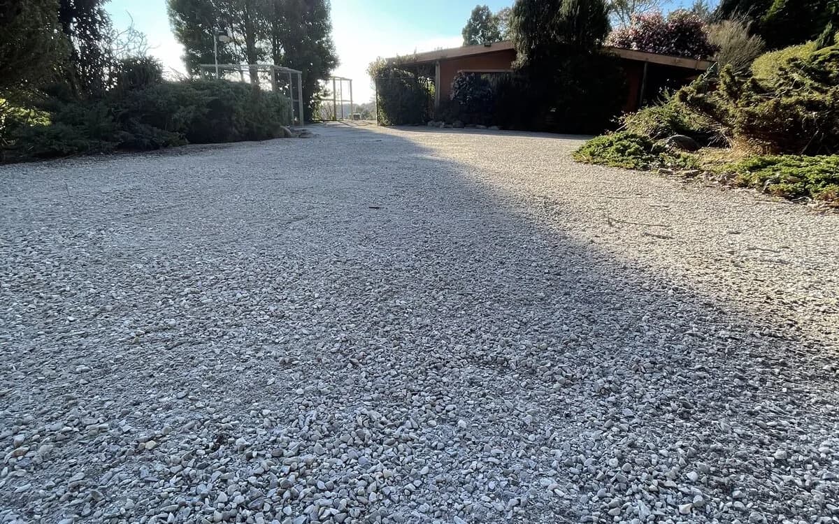 Wide crushed-rock driveway and turning area running up to a house