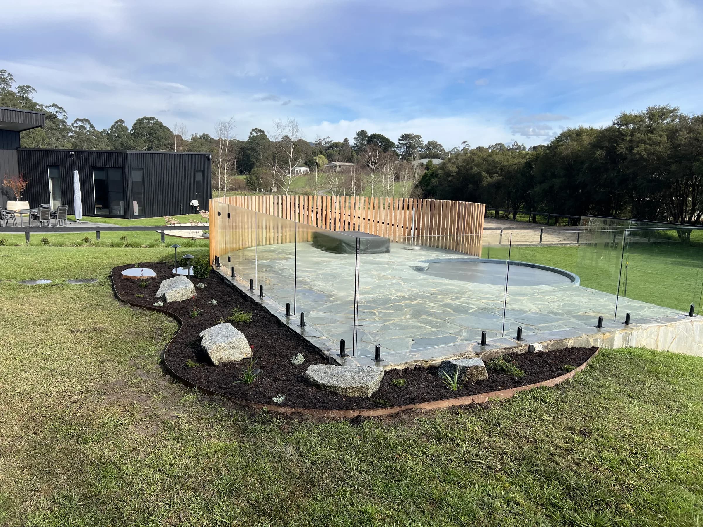 Pool surround with crazy paving, timber screen and boulder-edged beds